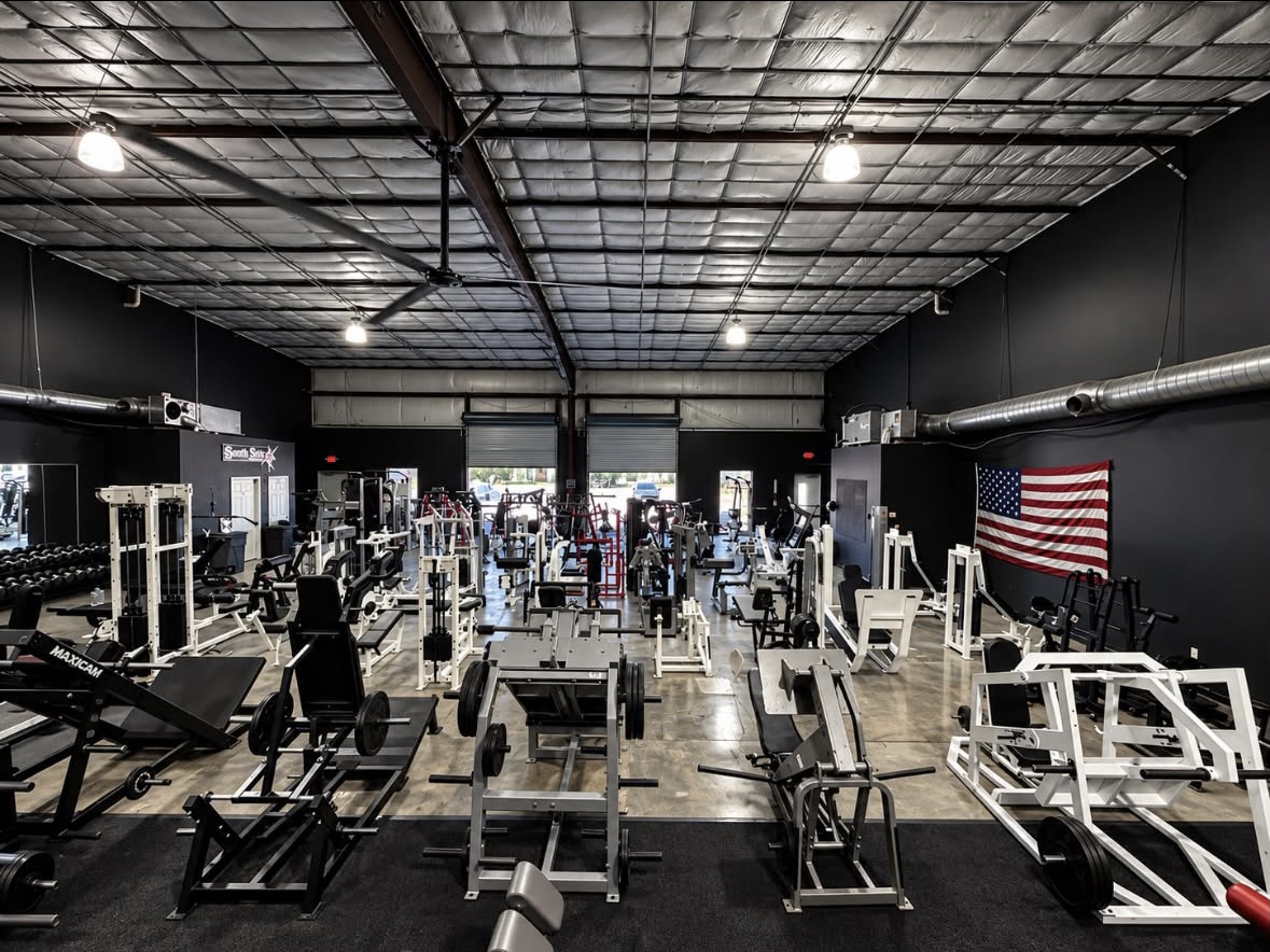 The new training floor, rows of machines under the warehouse roof, American flag on the back wall